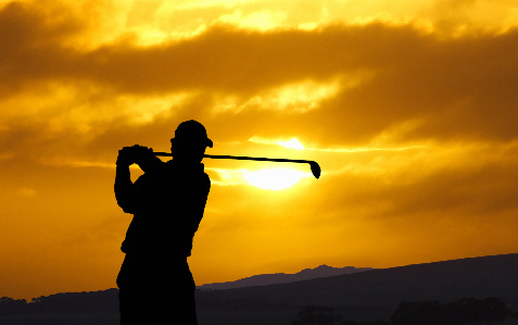 golfer swinging at sunset
